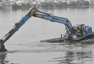 Pekerja menggunakan beko mengeruk lumpur yang mengendap di Waduk Pluit, Senin (13/6/2022). Pengerukan lumpur rutin ini dilakukan sebagai upaya mengurangi endapan serta tanaman liar dan mencegah banjir di kawasan tersebut. (merdeka.com/Iqbal S Nugroho)