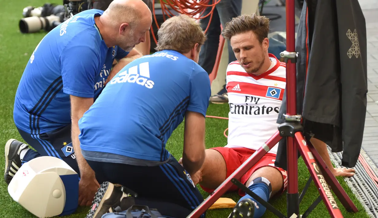 Gelandang Hamburg Nicolai Mueller menerima perawatan usai mencetak gol ke gawang Augsburg pada Divisi Satu Bundesliga di Hamburg, Jerman (20/8). Perayaan gol Mueller membuatnya cedera dan harus absen selama tujuh bulan. (AFP/PHBS/Daniel Bockwoldt)