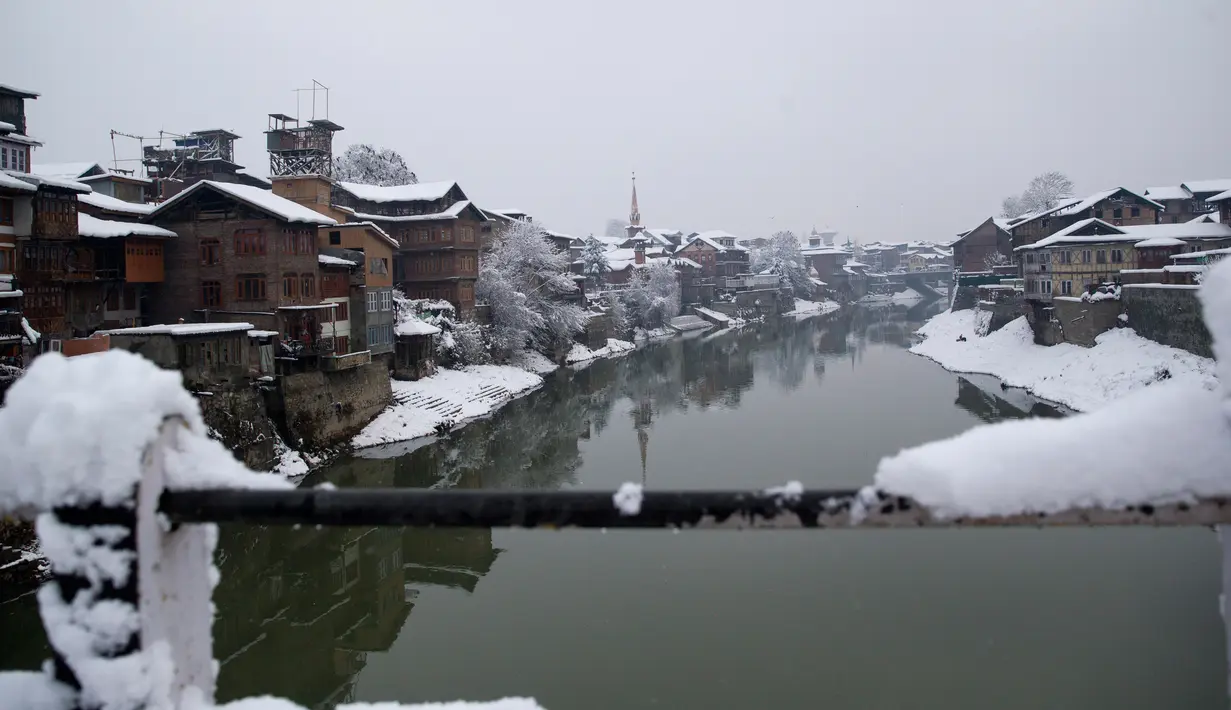Salju yang menyelimuti rumah-rumah di sepanjang Sungai Jhelum di Srinagar, Kashmir yang dikuasai India (7/1). Musim salju telah mengakibatkan gangguan lalu lintas udara dan lalu lintas jalan antara Srinagar dan Jammu. (AP Photo/Mukhtar Khan)