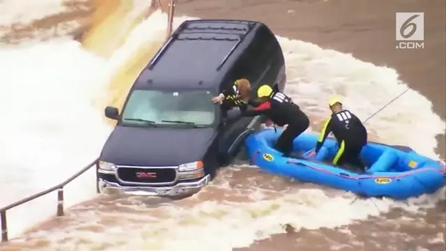 Sebuah video merekam penyelamatan seorang wanita di tengah arus banjir yang deras. Petugas keamanan menggunakan perahu karet untuk mendekat.