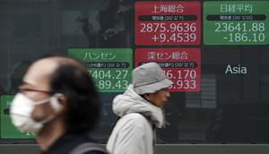 Orang-orang berjalan melewati layar monitor yang menunjukkan indeks bursa saham Nikkei 225 Jepang dan lainnya di sebuah perusahaan sekuritas di Tokyo, Senin (10/2/2020). Pasar saham Asia turun pada Senin setelah China melaporkan kenaikan dalam kasus wabah virus corona. (AP Photo/Eugene Hoshiko)
