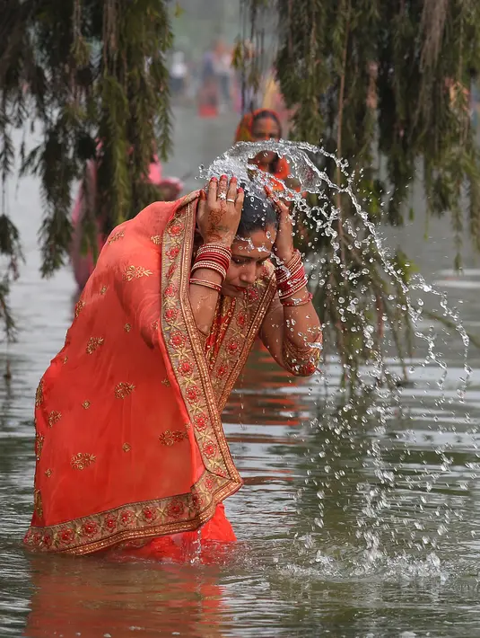 Seorang pemuja Hindu melakukan ritual mandi suci di kolam sekitar monumen India Gate dalam ritual pemujaan dewa matahari selama Festival Chhath Puja di New Delhi, Selasa (13/11). (Sajjad HUSSAIN / AFP)