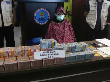 Pemilik rekening PT Surya Subur Jaya yang diduga terlibat dalam kejahatan TPPU, IN ditunjukkan beserta barang bukti uang di Kantor BNN, Jakarta, Selasa (17/7). BNN menyita total aset sebesar Rp 3,9 miliar. (Liputan6.com/Arya Manggala)