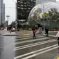 Pejalan kaki melewati The Spheres, kantor bernuansa hutan hujan yang baru dibuka Amazon, di Seattle, AS, Senin (29/1). The Spheres terdiri dari tiga rumah kaca berukuran bulat yang menaungi 40.000 jenis tanaman dari 400 spesies. (AP/Ted S. Warren)