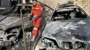 Seorang petugas medis berdiri di samping puing-puing mobil di kamp pengungsi Palestina Ain al-Hilweh, dekat Sidon di selatan Lebanon, pada Rabu 19 November 2025. Sebuah serangan udara Israel menghantam kamp pengungsi Palestina Ain al-Hilweh di Lebanon selatan. (Mahmoud ZAYYAT/AFP)