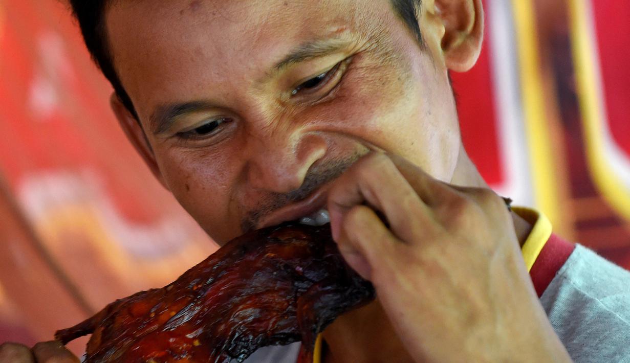 Seorang pria memakan tikus bakar di sebuah kios di provinsi Battambang, Kamboja (8/8/2019). Tikus bakar yang tusuk sate harganya masing-masing 0,25 USD atau sekitar 3500 rupiah. (AFP Photo/Tang Chhin Sotthy)