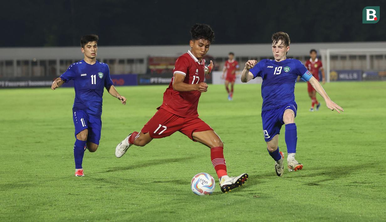 <p>Gelandang Timnas Indonesia U-20, Mufli Hidayat (tengah) melepaskan tendangan yang berusaha diblok kapten tim Uzbekistan U-20, Rustam Fomin (kanan) pada laga uji coba internasional di Stadion Madya, Senayan, Jakarta, Selasa (30/1/2024). (Bola.com/M Iqbal Ichsan)</p>