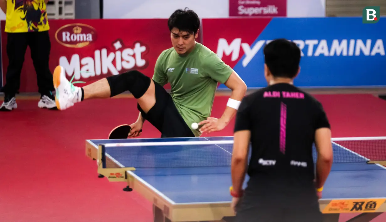 <p>Selebritas Rizky Billar (kiri) berusaha mengembalikan bola ke arah Aldi Taher pada laga tenis meja Turnamen Olahraga Selebriti Indonesia (TOSI) di GOR UNJ, Jakarta, Minggu (16/07/2023). Rizky Billar menang tiga set langsung atas Aldi Taher dengan skor 21-12, 21-15, 21-11. (Bola.com/Bagaskara Lazuardi)</p>