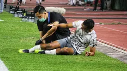 Irfan Jaya pun kesakitan dipinggir lapangan dan langsung mendapatkan perawatan dari tim medis Bali United. (Bola.com/Wahyu Pratama)