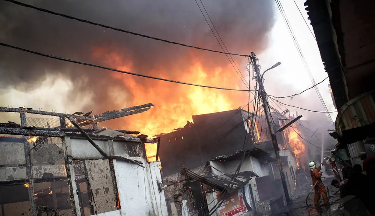 Warga berusaha memadamkan api pada kebakaran di Kompleks Bearland, Kelurahan Kebon Manggis, Matraman, Jakarta, (14/10/14). (Liputan6.com/Faizal Fanani)