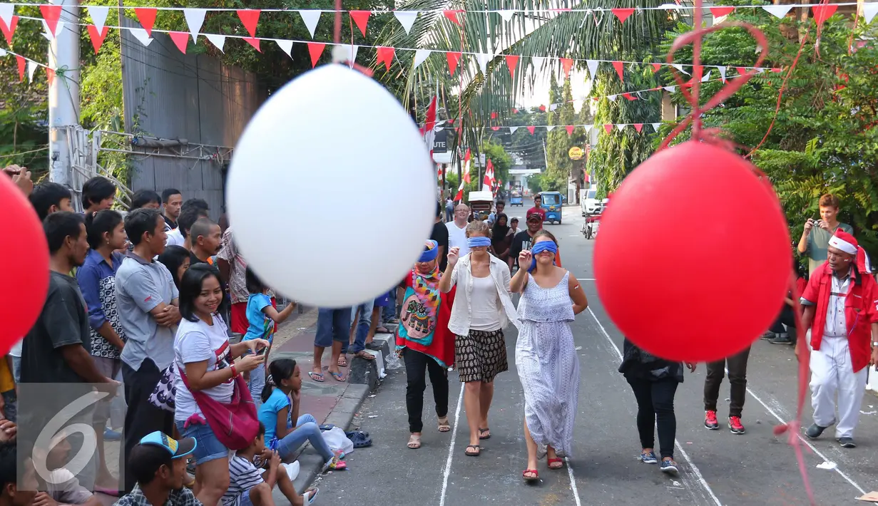 Sejumlah WNA mengikuti lomba tusuk balon di Jalan Jaksa, Jakarta, Rabu (17/8). Perlombaan ini digelar dalam rangka memperingati HUT RI ke-71. (Liputan6.com/Angga Yuniar)