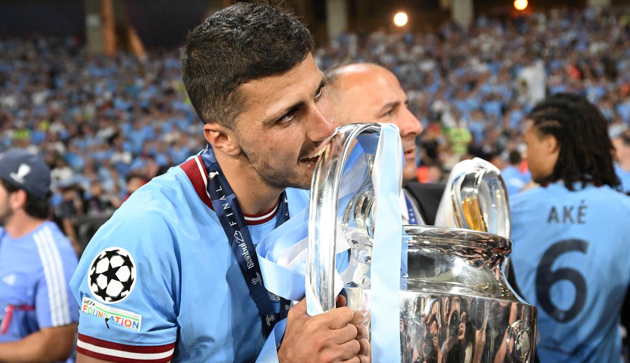 Gelandang Manchester City, Rodri menggigit trofi Liga Champions dalam perayaan kemenangan atas Inter Milan pada laga Final Liga Champions 2022/2023 di Ataturk Olympic Stadium, Istanbul, (10/6/2023). Gelar ini juga menjadi yang pertama bagi pencetak gol tunggal kemenangan Man City atas Inter Milan. (AFP/Paul Ellis)