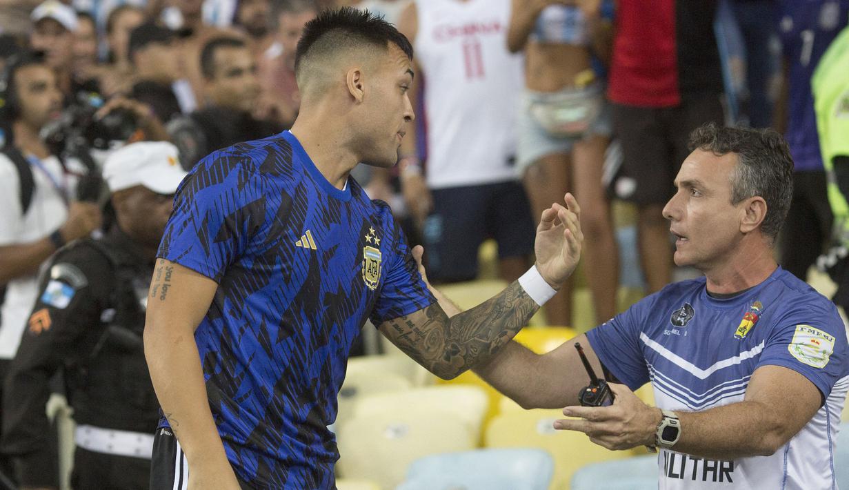 Pemain Argentina, Lisandro Martinez (kiri) berbicara dengan petugas keamanan saat kericuhan sebelum laga Kualifikasi Piala Dunia 2026 antara Brasil melawan Argentina di Stadion Maracana, Brasil, Rabu (22/11/2023) WIB. (AFP/Carl De Souza)