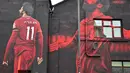 Seseorang berolahraga melewati mural seniman John Culshaw yang menggambarkan pesepak bola Mohamed Salah di fasad bangunan dekat Stadion Anfield, Liverpool, Rabu (30/3/2022). Salah tidak diragukan lagi, adalah salah satu pemain terhebat yang pernah mengenakan seragam Liverpool. (Paul ELLIS / AFP)