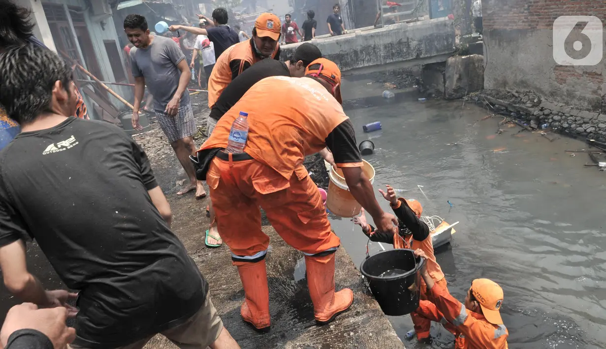 Petugas PPSU dan warga membantu menjinakkan kebakaran yang melahap permukiman di Jalan Kebon Jeruk 13, Taman Sari, Jakarta Barat, Minggu (6/10/2019). Kebakaran menghanguskan puluhan rumah di dua kelurahan, Taman Sari dan Mapar. (merdeka.com/Iqbal Nugroho)