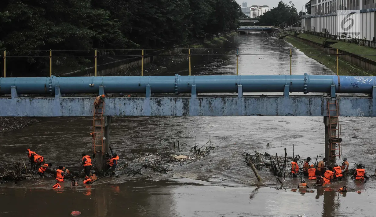 Pasukan oranye membersihkan sampah yang tersangkut di aliran sungai Ciliwung di kawasan Sudirman, Jakarta, Jumat (9/2). Meningkatnya debit air di Bendungan Katulampa, aliran air yang masuk ke Sungai Ciliwung membawa sampah. (Liputan6.com/Faizal Fanani)