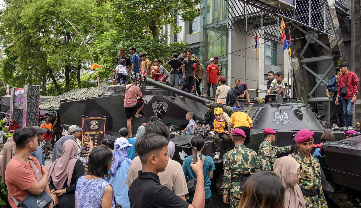 Beberapa anak terlihat senang ketika menaiki kendaraan tempur yang dipamerkan. Tampak dalam foto, warga berfoto bersama kendaraan militer selama Pameran Marinir Indonesia, yang menandai peringatan Hari Ulang Tahun ke-80 Korps Marinir TNI AL di Surabaya, Jawa Timur pada Minggu 9 November 2025. (JUNI KRISWANTO/AFP)