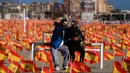Sepasang suami istri ber-wefie saat mereka duduk di antara ribuan bendera Spanyol yang mewakili korban COVID-19, di pantai Patacona, Valencia pada Minggu (4/10/2020). Virus corona di Spanyol sejauh ini telah merenggut lebih dari 32.000 nyawa dan 790.000 kasus terkonfirmasi. (Jose Jordan / AFP)