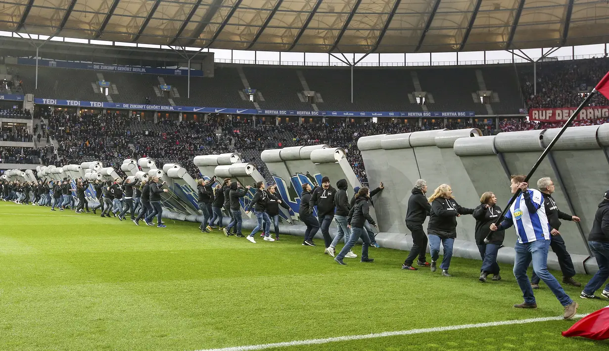 Para penggemar merobohkan replika Tembok Berlin pada hari peringatan 30 tahun runtuhnya Tembok Berlin sebelum pertandingan Hertha Berlin melawan RB Leipzig di Stadion Olimpiade, Berlin (9/11/2019). Tembok tersebut didirikan pada 1961 dan diruntuhkan 1989. (Andreas Gora/dpa via AP)