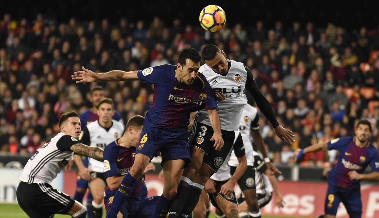 Gelandang Barcelona, Sergio Busquets, duel udara dengan bek Valencia, Ruben Vezo, pada laga La Liga Spanyol di Stadion Mestalla, Valencia, Minggu (26/11/2017). Kedua klub bermain imbang 1-1. (AFP/Jose Jordan)