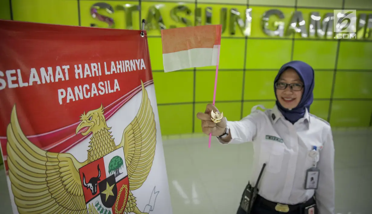 Petugas PT KAI DAOP 1 menunjukan pin garuda di Stasiun Gambir, Jakarta, Kamis (1/6). Dalam rangka memperingati HUT Pancasila PT KAI Daop 1memberikan pin dan bendera merah putih kepada penumpang kereta api. (Liputan6.com/Faizal Fanani)