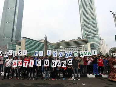 Sejumlah orang yang tergabung dalam Koalisi Pilkada Damai Tanpa Kecurangan (KPD-TK) memegang tulisan Pilkada Damai Anti Curang di kawasan hari bebas kendaraan di Bundaran HI, Jakarta, Minggu (2/4). (Liputan6.com/Johan Tallo)
