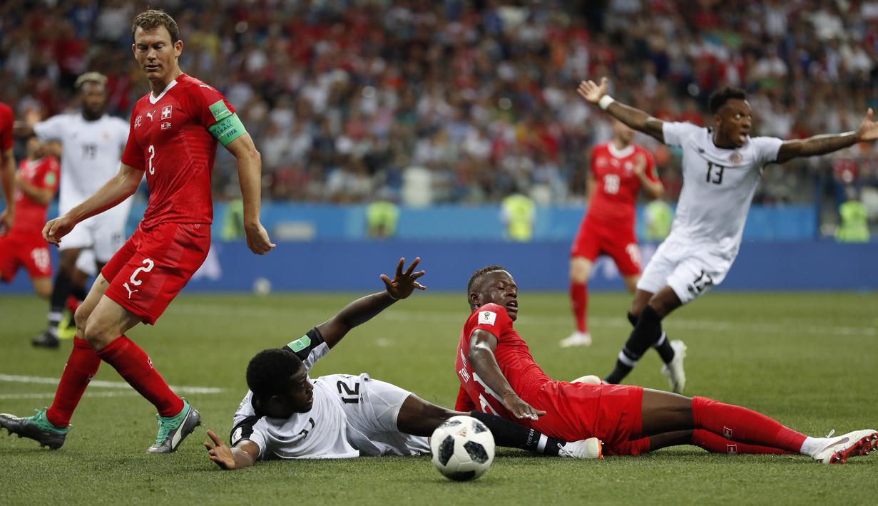 Pemain Kosta Rika, Joel Campbell (2kiri) dijegal pemain Swiss, Denis Zakaria pada laga grup E Piala Dunia 2018 di Nizhny Novgorod Stadium, Nizhny Novgorod, Rusia, (27/6/2018). Swiss bermain imbang 2-2. (AP/Natasha Pisarenko)
