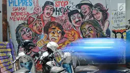 Sejumlah motor terparkir dekat mural pemilu di Jalan Karet, Depok, Jawa Barat, Rabu (20/3). Mural itu mengajak masyarakat untuk berpartisipasi dalam menyukseskan pemilu dengan cara damai dan menjaga meski berbeda pilihan. (Liputan6.com/Herman Zakharia)
