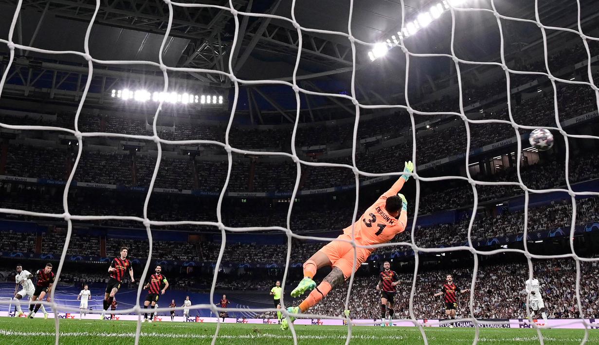 Penjaga gawang Manchester City, Ederson Moraes (kanan), gagal menepis tendangan pemain Real Madrid, Vinicius Junior (kiri), dalam pertandingan leg pertama Liga Champions 2022/2023 yang berlangsung di Santiago Bernabeu stadium, Rabu (10/5/2023) dini hari WIB. (AFP/Javier Soriano)