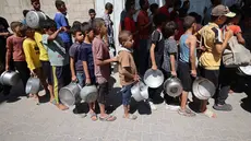 Anak-anak Palestina mengantre untuk menerima makanan panas dari dapur amal kamp pengungsi Nuseirat di Jalur Gaza yang dikepung Israel pada 11 September 2025. (Eyad BABA/AFP)