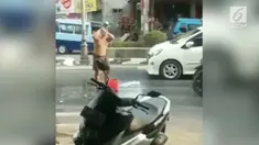 Seorang pemuda nekat mandi sekaligus keramas di tengah jalan. Belum diketahui maksud dari aksi tersebut.