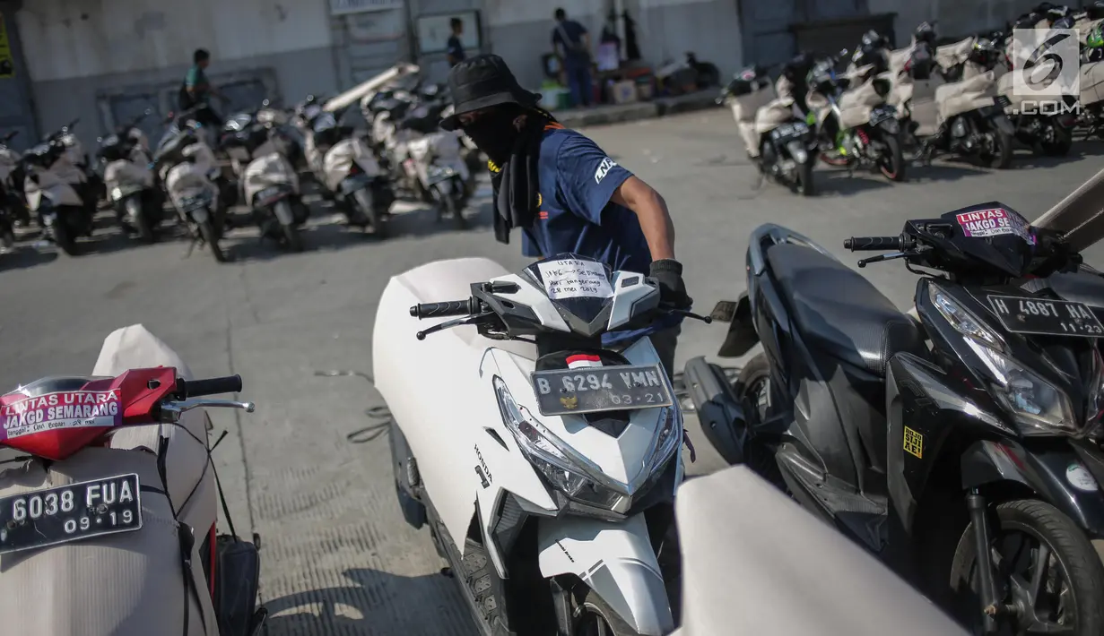 Pekerja membungkus motor pemudik sebelum dikirim dengan kereta api di Stasiun Jakarta Gudang, Selasa (28/5/2019). Direktorat Lalu Lintas dan Angkutan Kereta Api Kementerian Perhubungan mengangkut 18.096 motor pemudik secara gratis pada mudik Lebaran 2019. (Liputan6.com/Faizal Fanani)