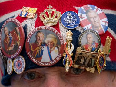John Loughrey mengenakan topi yang dihiasi dengan memorabilia kerajaan sambil berdiri di sepanjang rute Penobatan Raja di The Mall di London, Selasa, 2 Mei 2023. (AP Photo/Vadim Ghirda)