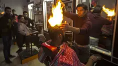 Ramadan Edwan, seorang tukang cukur asal Palestina, menggunakan api untuk mencukur rambut pelanggannya di sebuah barbershop di kamp pengungsian Rafah, di selatan Jalur Gaza, Rabu (1/2). (MAHMUD HAMS/AFP)