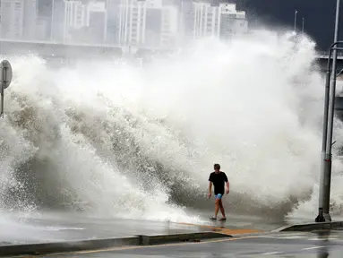 Seorang pria berjalan di pinggir pantai saat gelombang besar yang disebabkan oleh topan Chaba di Busan, Korea Selatan, 5 Oktober 2016. Topan Chaba berkecepatan 180 km per jam ini menyebabkan banjir bandang di Kota Busan. (REUTERS/Park Cheol-hong)