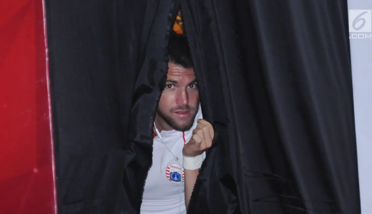 Pemain Persija asal Kroasia, Marko Simic mengintip jelang memeragakan kaus latihan tim saat peluncuran di Jakarta, Jumat (2/2). Secara resmi, Persija memperkenalkan tiga model kaus yang akan digunakan pada musim 2018. (Liputan6.com/Helmi Fithriansyah)