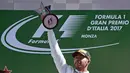 Pembalap Mercedes Lewis Hamilton mengangkat trofi usai memenangkan balapan F1 GP Italia, di arena Monza, Italia (3/9). (AFP Photo/Miguel Medina)