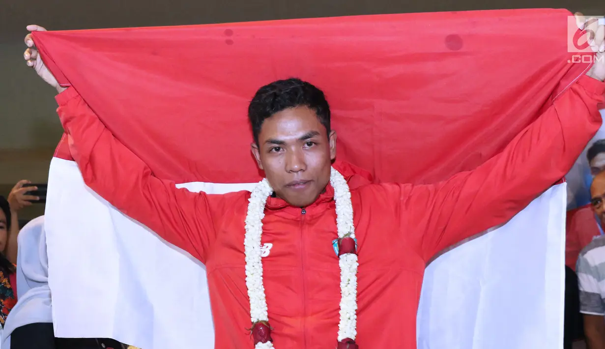 Pelari muda Indonesia, Lalu Muhammad Zohri membentangkan bendera Merah Putih saat penyambutan di Terminal 3 Bandara Soetta, Tangerang, Selasa (17/7). Lalu M Zohri meraih emas lari 100m putra di Kejuaraan Dunia U-20 IAAF. (Liputan6.com/Helmi Fithriansyah)