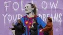 Sejumlah pejalan kaki melintasi mural bergambar Alexia Putellas yang dibuat oleh seniman Italia, TvBoy di Barcelona, 20 Maret 2022. (AFP/Josep Lago)