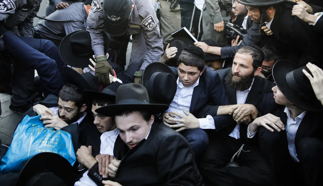 Pasukan keamanan Israel berusaha membubarkan demonstran di Yerusalem (17/10). Dalam aksinya, para demonstran memblokir jalan utama untuk menentang wajib militer Israel. (AFP Photo/Menahem Kahana)