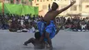 Seorang pegulat merayakan kemenangan setelah mengalahkan lawannya dalam turnamen gulat tradisional Sindhi Malakhra di kota pelabuhan Karachi, Pakistan pada Minggu (13/12/2020). Gulat kuno yang dimulai sejak 5.000 tahun lalu ini salah satu olahraga favorit di kalangan pria. (Photo by Asif HASSAN / AF