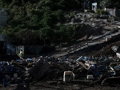 Seorang pekerja membawa balok kayu selama operasi pembongkaran kota kumuh distrik "Talus 2" di Koungou, di pulau Mayotte, Samudra Hindia Prancis, pada 23 Mei 2023. (AFP/PHILIPPE LOPEZ)