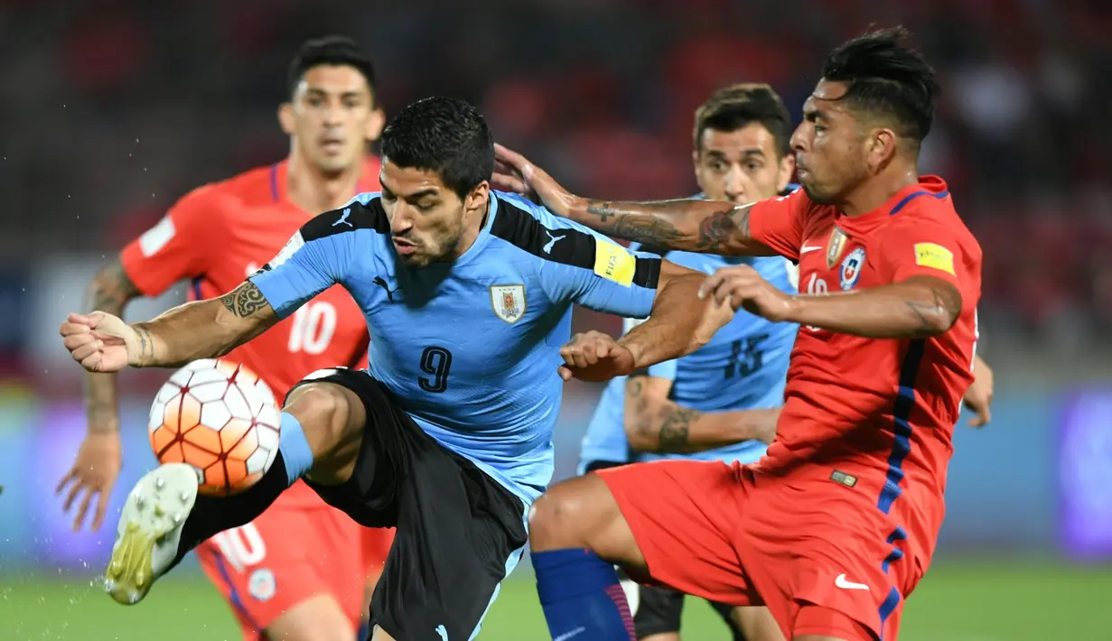 Striker Uruguay asal klub Barcelona, Luis Suarez, dijaga ketat pemain Cile pada laga Kualifikasi Piala Dunia 2018 zona CONMEBOL di Stadion Nasional Julio Martinez Pradanos, Santiago, Rabu (16/11/2016) pagi WIB. (AFP/Martin Bernetti)