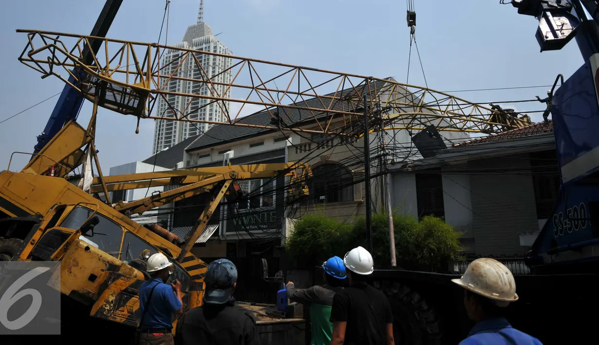 Pekerja mengevakuasi crane yang jatuh di Jalan Kyai Maja, Jakarta Selatan, Kamis (15/10/2015). Alat besar yang tengah melakukan proyek ‎jalan layang ini menimpa salah satu rumah warga yang berada di sisi kanan jalan. (Liputan6.com/Helmi Afandi)