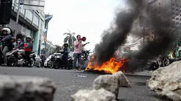 Massa menggelar orasi sambil membakar ban dan memblokade jalan raya Cikini, Jakarta, Selasa (18/11/2014). (Liputan6.com/Faizal Fanani)