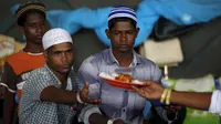 Para pengungsi etnis Rohingya saat menerima makanan di tempat penampungan, Kuala Langsa, Aceh (25/5/2015). Pemerinta RI mengalokasikan bantuan sebesar Rp 2,3 Miliar untuk pengungsi Rohingya yang berada di Aceh. (Reuters/Darren Whiteside)