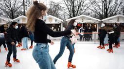 Pengunjung memakai masker untuk mencegah penyebaran COVID-19 saat bermain ice skating di pasar malam di Paris, Prancis, 29 Desember 2021. Lonjakan kasus baru COVID-19 di Prancis turut diakibatkan varian Omicron. (AP Photo/Thibault Camus)