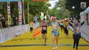 Peserta melewati garis finish pada lomba lari BNI UI Half Marathon di kampus UI Depok, Minggu (15/7). Kegiatan yang diikuti 3.600 peserta digelar untuk menyambut perhelatan Asian Games 2018. (Liputan6.com/HO/Palar)