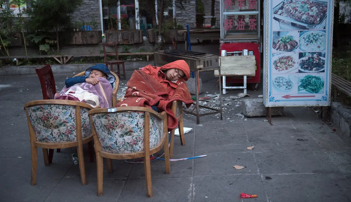 Warga tidur di luar rumah mereka di Zhangzha, provinsi Sichuan, China barat daya, Kamis (10/8). Sejumlah warga memilih menghabiskan malam di luar rumah setelah gempa 6,5 SR mengguncang wilayah tersebut dan menewaskan belasan orang. (Nicolas ASFOURI/AFP)