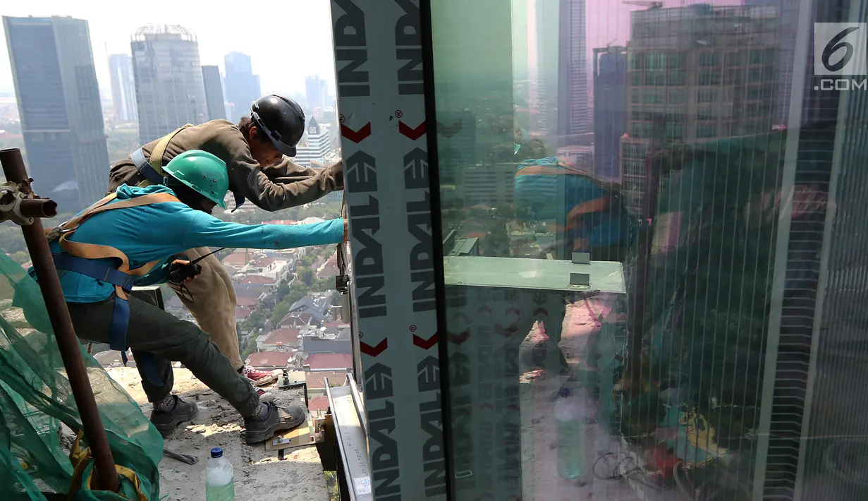 Pekerja Nusa Konstruksi Enjiniring memasang kaca gedung World Capital Tower, di Mega Kuningan, Jakarta, Rabu (13/9). Menurut Riset Colliers International Indonesia dua tahun mendatang, 58 gedung perkantoran akan hiasi Jakarta. (Liputan6.com/Fery Pradolo)